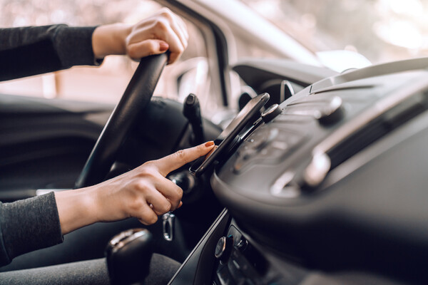 A person driving pressing a button on a mounted smartphone.