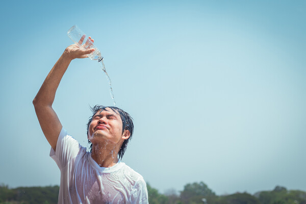 A young person pouring water over their head.