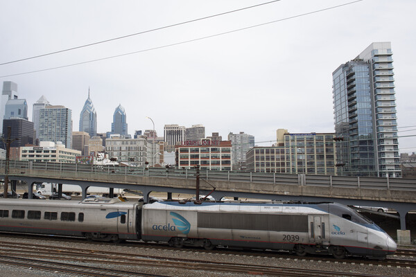 An Amtrak Acela train with the Philadelphia city skyline in the background