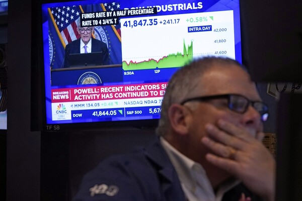 A stock trader is seen monitoring a screen showing Federal Reserve Chair Jerome Powell's announcement of a half-percentage point interest rate cut