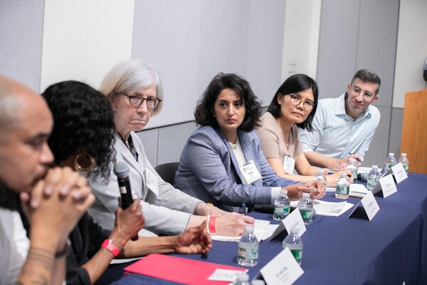 A group of people listening at a table. 