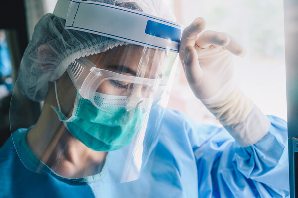 Nurse in full PPE including a face shield.