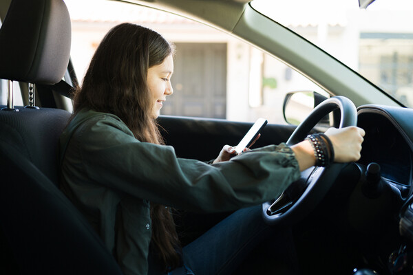 A teenager looking at a cellphone while driving.