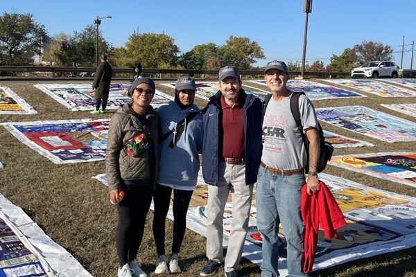 Four people in front of National AIDS Memorial Quilt.