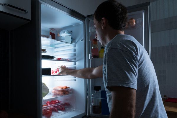 A person taking food out of the fridge late at night.