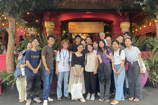 Group of students and professor pose for a photo in front of a restaurant.