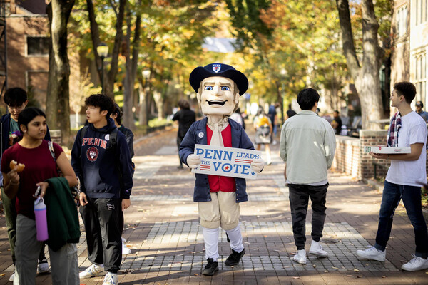 The Penn Quaker holding a Penn Leads the Vote sign on Locust Walk.