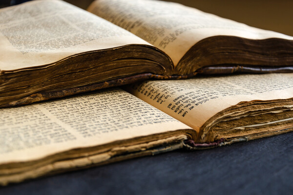 Two ancient Hebrew bibles open on a table.