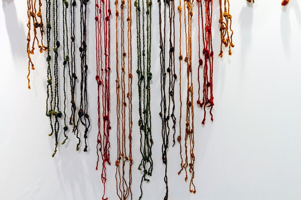 A colorful Quipu (abacus inca) hanging on a wall.