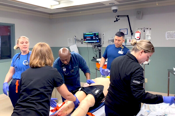 A Navy trauma team in a hospital room doing triage on a mannequin.