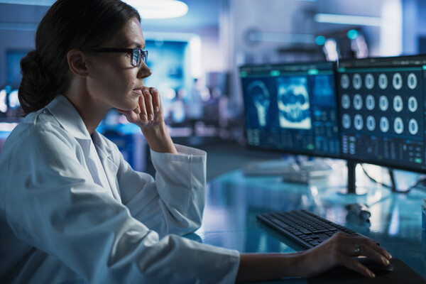 A researcher looking at brain scans on a computer in a lab.