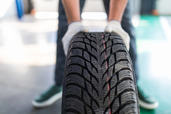 A gloved mechanic holds a new tire.