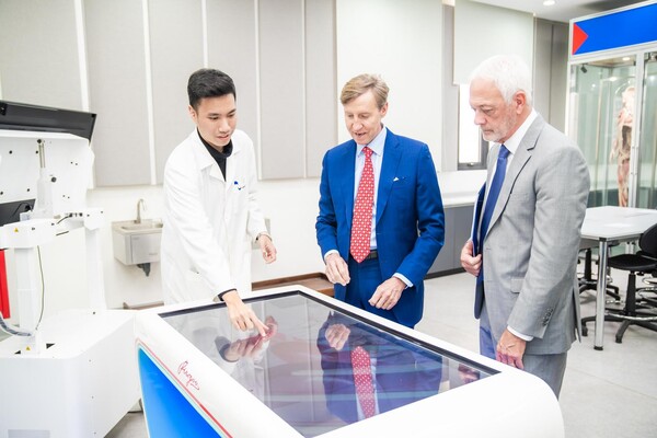 Interim Penn President J. Larry Jameson in a lab examining a piece of equipment. 