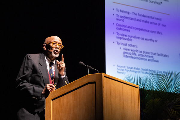 Orlando Patterson speaks at a podium. Behind him, a screen shows the five fundamental principals of social beings