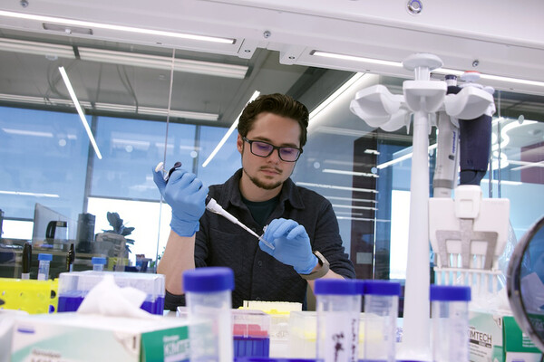 Tyler Daniel using a pipette in a bioengineering lab.