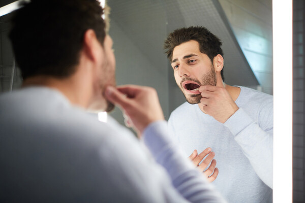 A person checking their gum health and teeth in a mirror.