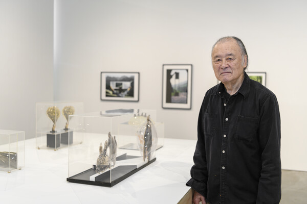 Artist Carl Cheng standing in art gallery with sculptures and photographs