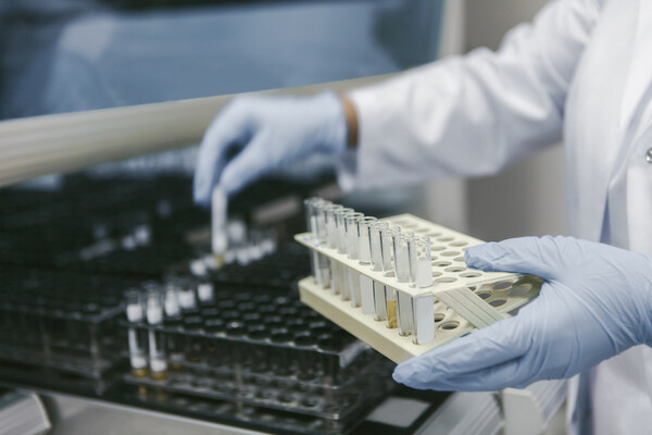 A gloved medical researcher handling pipettes in a lab.