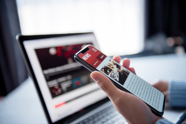 person's hand holding a phone with a news story visible