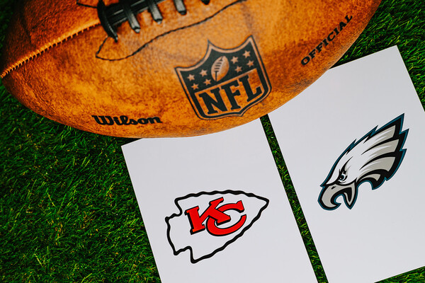 A football on a field atop a Kansas City and Eagles logo.