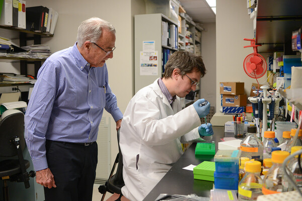 Aguirre and Murgiano working in a lab with pipettes.