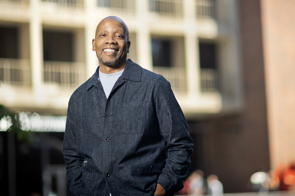 Lance Freeman stands with hands in pockets outside of a building.