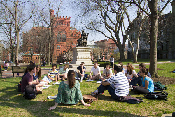 A group of students sitting outside on the lawn of College Green.