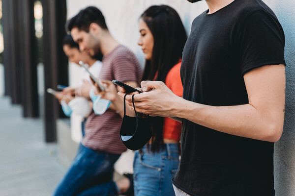 Four friends holding their face masks in their hands looking at the phone.