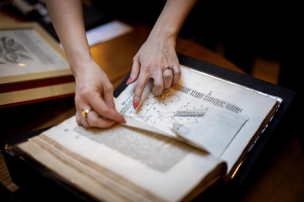 Hands flipping through copy of Micrographia.