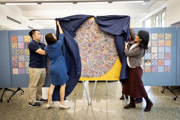 Mei Long, Vicki Aquino, and another person unveil the new PAACH mural at the ARCH building.