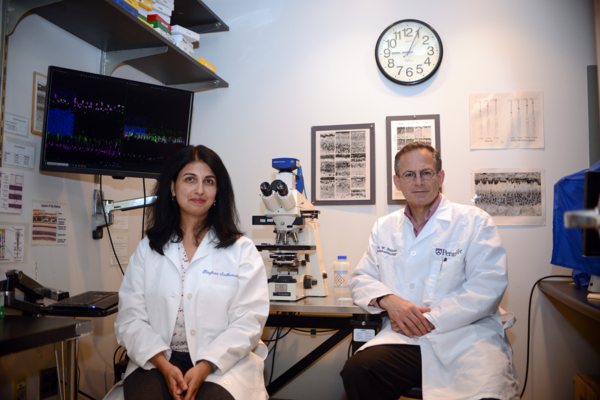 Raghavi Sudharsan and William Beltran by a microscope in a lab.