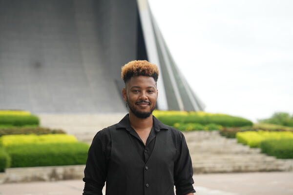 Timethius Terrell standing upright in a bright outdoor setting, while smiling and facing forward.
