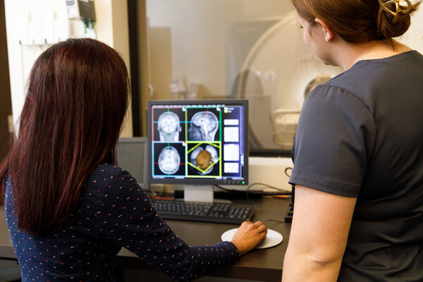 Two medical personnel looking at an fMRI image on a computer.