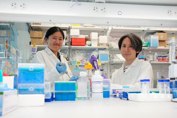 Emily Han and Dongyoon Kim in the research lab filled with bottles and other lab equipment..