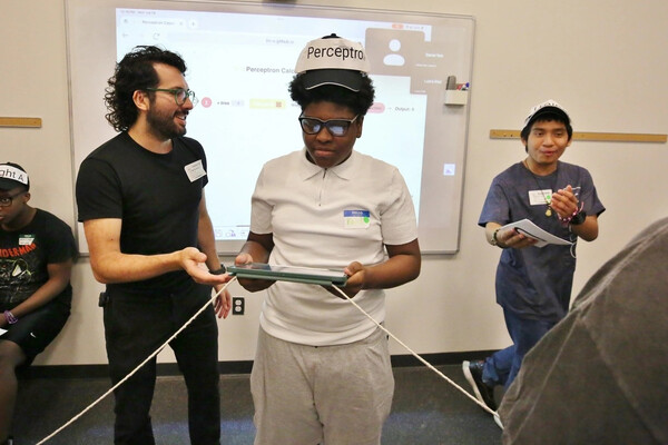 Morales-Navarro assists a student who holds a computer tablet