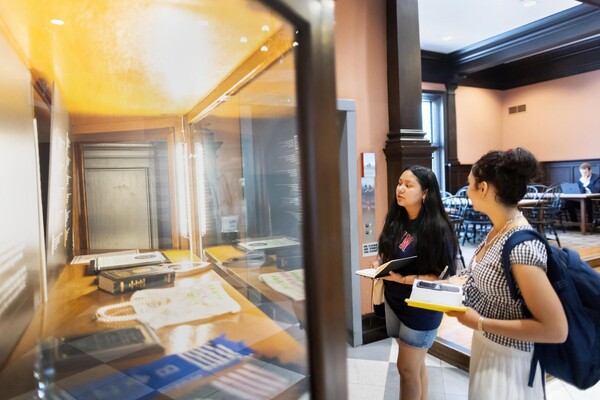 Wendy Hernandez Higarede and Veronica Baladi look at glass case in Houston Hall.