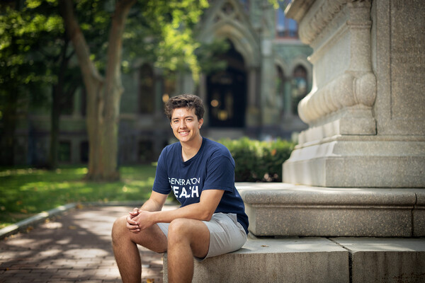 Cole DuHaime leans against a statue outside College Hall.