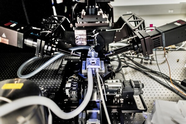 Imaging devices surround a material on a blue backlit surface.