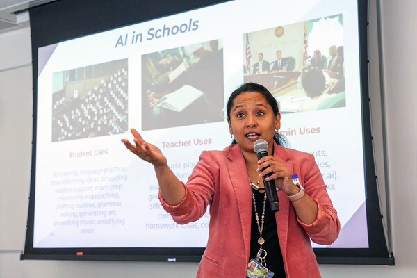 Betty Chandy speaking into a microphone with AI In Schools on the white board behind her.