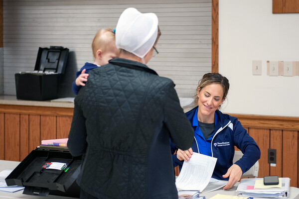 Jennifer N. Carter checks in an Amish patient carrying a child at the Lancaster clinic.