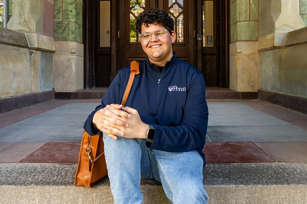 Noah Royal Milad seated on the steps of College Hall.