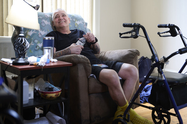 Mike Desalis seated at home next to his walker.