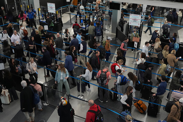 Travelers in a busy security checkpoint at an airport.
