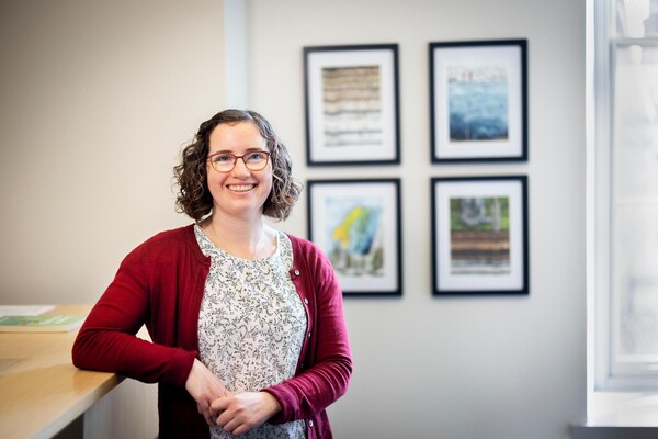 Melissa Charenko stands in front of art in her office.