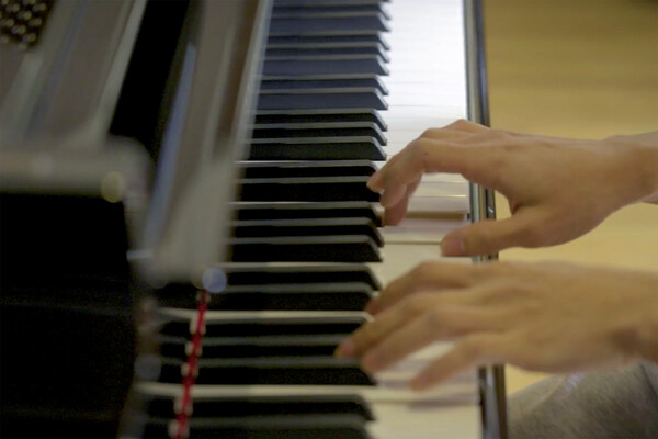 Hands playing a piano.