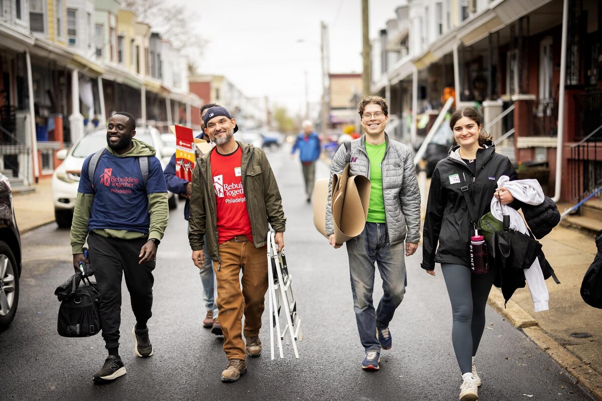 Volunteers smiling and carrying tools and supplies during the block build event.