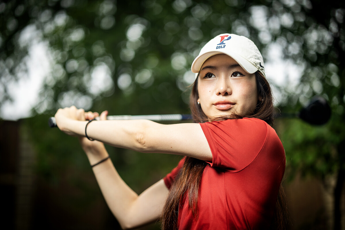 Julie Shin holds her club after swinging while wearing her Penn uniform.