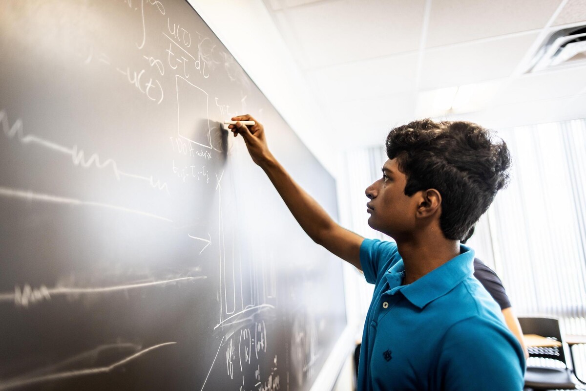 Chinmay Govind writing equations on a chalkboard.
