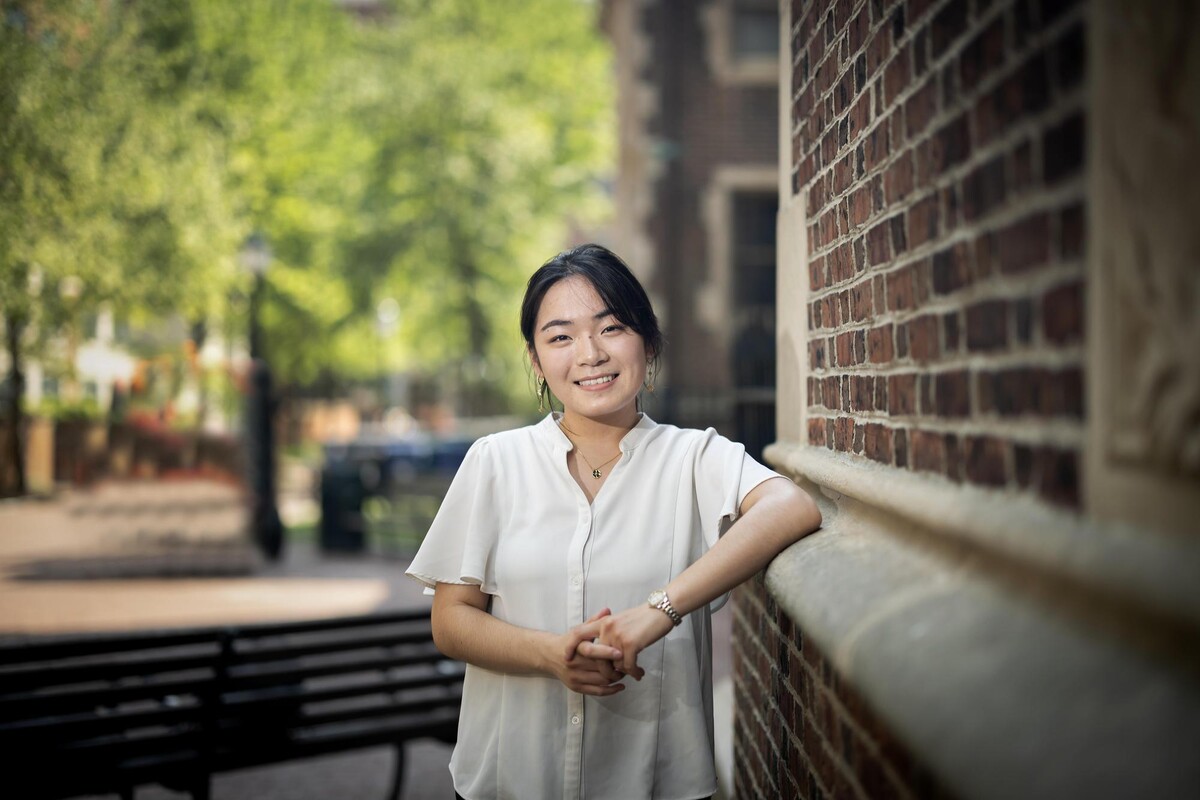 Eri Maeda standing outdoors against a brick wall and smiling, facing forward.
