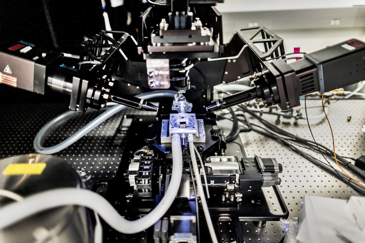 Imaging devices surround a material on a blue backlit surface.
